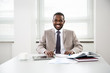 © chagin - Happy handsome african american businessman smiling while looking at camera in office