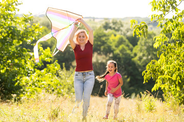 Wall Mural - young woman and girl flying a kite