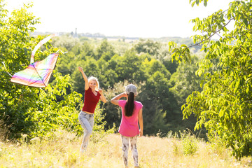 Wall Mural - Young woman and girl flying a kite