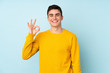 © luismolinero - Teenager caucasian handsome man isolated on purple background showing ok sign with fingers