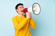 © luismolinero - Teenager caucasian handsome man isolated on purple background shouting through a megaphone