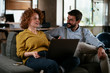 © JustLife - Businesswoman and businessman sitting and talking in office. Young woman and man working on laptop.