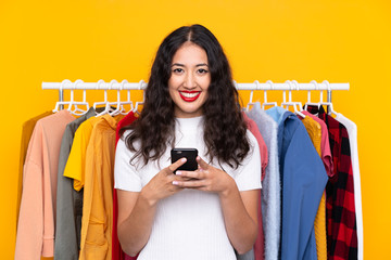 Sticker - Mixed race woman in a clothing store and talking to mobile