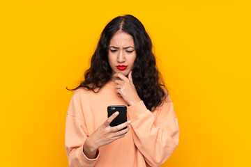 Wall Mural - Spanish Chinese woman over isolated yellow background thinking and sending a message