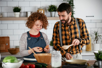 Wall Mural - Boyfriend and girlfriend making delicious food at home. Loving couple cooking in kitchen..