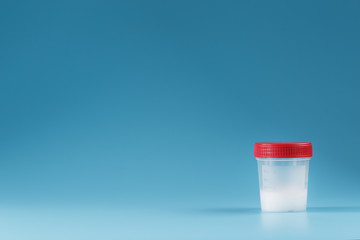 Semen in a test container with a red lid on a blue background.