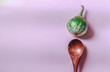 Conceptual photo of a kermit eggplant and wooden spoon on a pink background to show concept of wellness, veganism, clean living and  nutrition