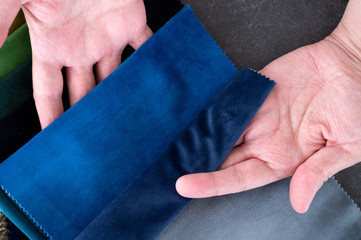 Top down view of two white male hands holding blue samples of velvet