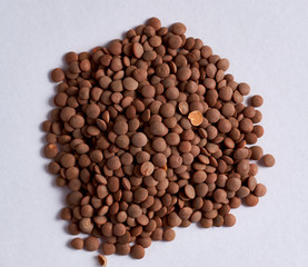 Poster - Top view closeup of a pile of brown lentils on a white surface