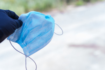 Sticker - Person holding a blue protective face mask with a blurry background