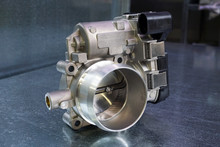 New Throttle Valve Of A Modern Car Engine On A Steel Background. Car Service And Spare Parts.   