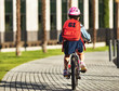 © JenkoAtaman - Rear view of a schoolgirl riding a bicycle to school.