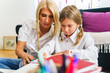 © Miljan Živković - Front view portrait of single mother and daughter at home doing homework - Woman helping her child with education - Back to school support learning childhood growing up concept