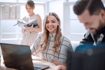 Poster - young business woman sitting at office Desk