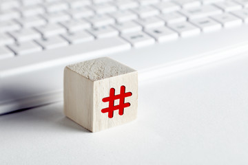 Wall Mural - Hashtag symbol on a wooden cube with computer keyboard background on white