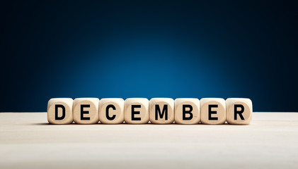 Wall Mural - The month December written on wooden cubes against blue winter background with copy space. Month of the year.