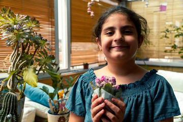 Young girl holding a .small pot of flowers and smiling