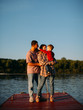 © Georgii - Young family hug each other standing on dock. Summer photography for blog or advertising about family and travel