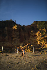 Poster - Vertical shot of a young female doing a trick on seashore sands