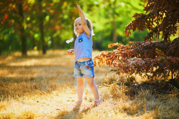 Wall Mural - Adorable toddler girl having fun in autumn park