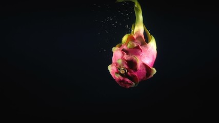 Wall Mural - Video of falling pitahaya in the water on black background