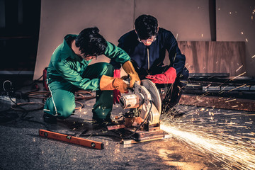 Professional mechanic man is cutting steel metal with rotating carbon blade cutter. Steel industry and workshop concept.