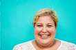 © DisobeyArt - Happy plus-size woman portrait - Curvy overweight person with turquoise background - Emancipation and confident concept - Focus on face