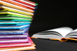 Edukacja - lektury szkolne, książki ułożone jedna na drugą w kolorach tęczy na ciemnym tle