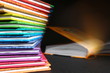 Domowa biblioteka - książki w kolorowych okładkach ułożone w kolumnie, otwarta książka w tle