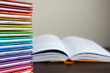 Kolorowe książki ułożone w stos, otwarta książka w tle