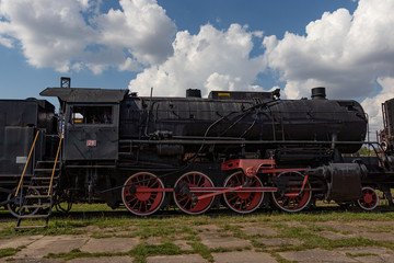 vintage steam engine train under sunny blue sky with clouds