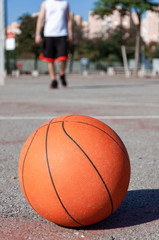 Canvas Print - Vertical selective focus shot of a basketball ball in a court and a person in the background