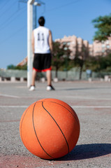 Canvas Print - Vertical selective focus shot of a basketball ball in a court and a person in the background