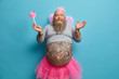 © wayhome.studio  - Positive man in princess outfit, wears pleated rosy skirt, wings and undersized t shirt, holds magic wand, prepares for carnival or costume party, has big tattooed belly, waits for miracle happened