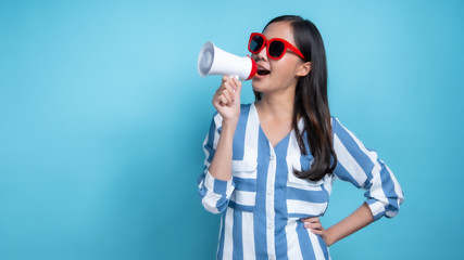 Beautiful Asian woman wearing red glasses holding white megaphone to yell and announce for present product , present big sell in long copy space