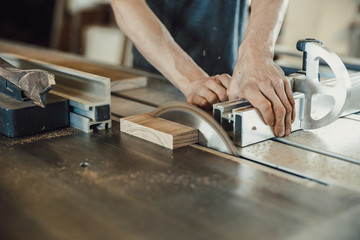 Canvas Print - Carpenter cutting a piece of wood with a machine