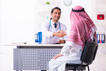 Wall Mural - Old male arab visiting young male doctor