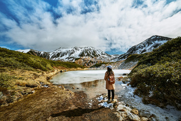 asian woman is standing at swamp that is named midorigaike in tateyama-kurobe alpine route or japan 
