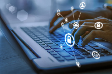 Business, technology, internet and networking concept. Young businesswoman working on his laptop in the office, select the icon security on the virtual display.Blue tone concept