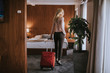 © BGStock72 - Young businesswoman arrives in a hotel room with red suitcase