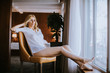 © BGStock72 - Young blond woman sitting in chair by window at day light