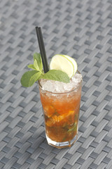 Poster - Vertical shot of non-alcoholic drink  with lime, mint and crushed ice on a plastic woven surface