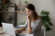 © fizkes - Smiling young Caucasian woman sit at desk look at laptop screen browsing surfing wireless internet, happy female busy working studying on computer online, text message on gadget, technology concept