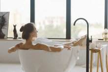 Young Beautiful Woman Having Bubble Bath And Looking At Window.
