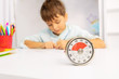 Timer and little boy during development therapy lesson draw on paper on background