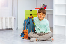 Smiling Calm Little Boy Sit In His Room With Positive Expression Holding School Rucksack