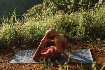 Wall Mural - Young woman in sports wear  exercising in park, practise yoga asana in summer park, stretching