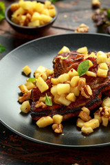 Wall Mural - Roasted Pork chops with caramelized apples, walnuts and sage in black plate on wooden table