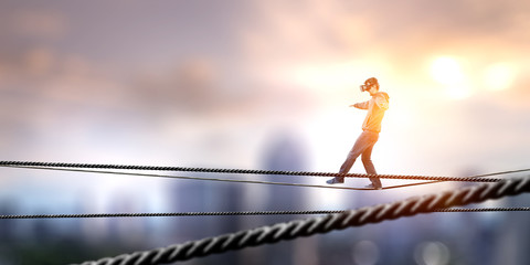 Wall Mural - Man wearing virtual reality goggles and balancing on rope