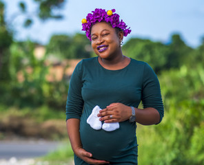 Wall Mural - African American pregnant female holding cute white baby socks on her belly